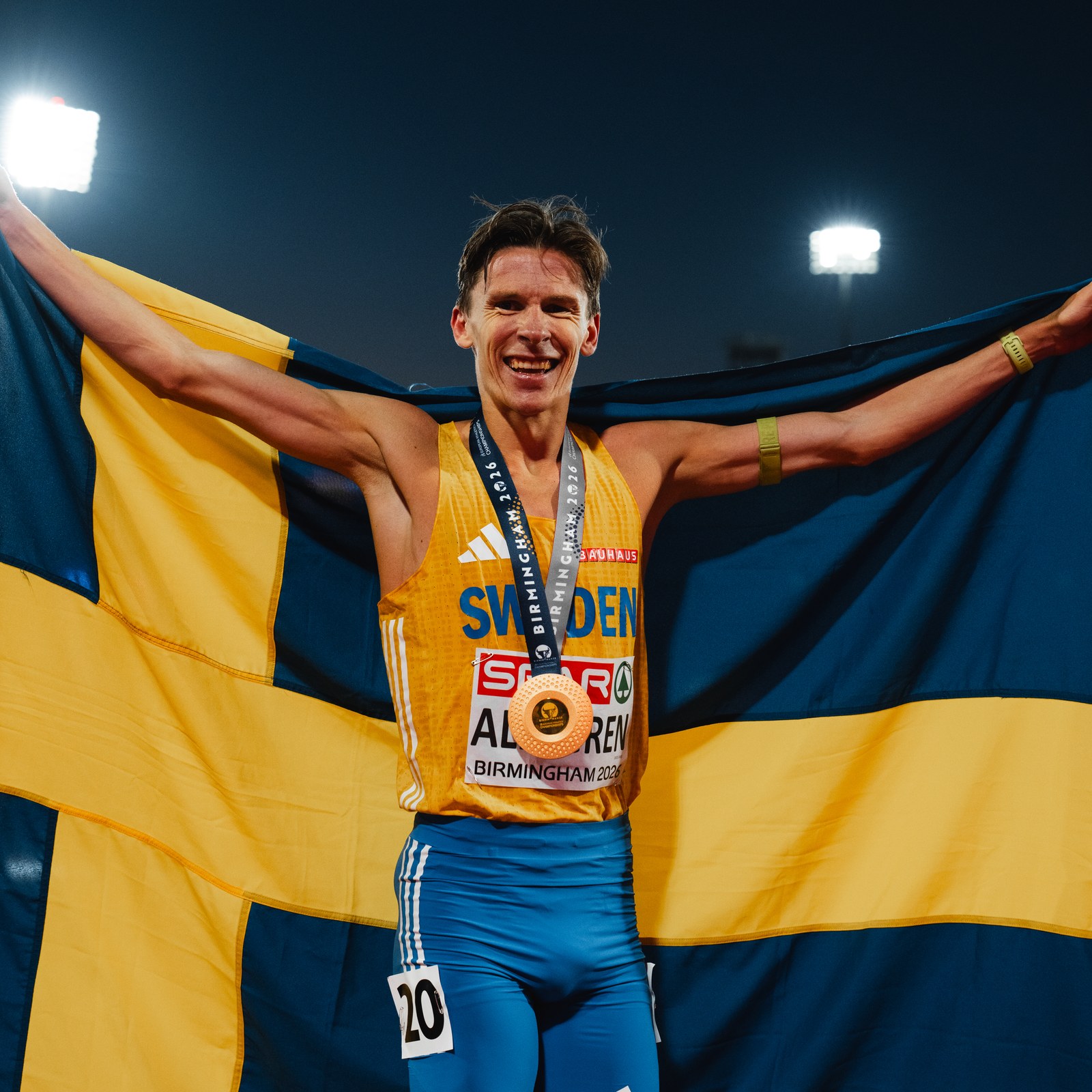 Andreas Almgren med medalj och den svenska flaggan