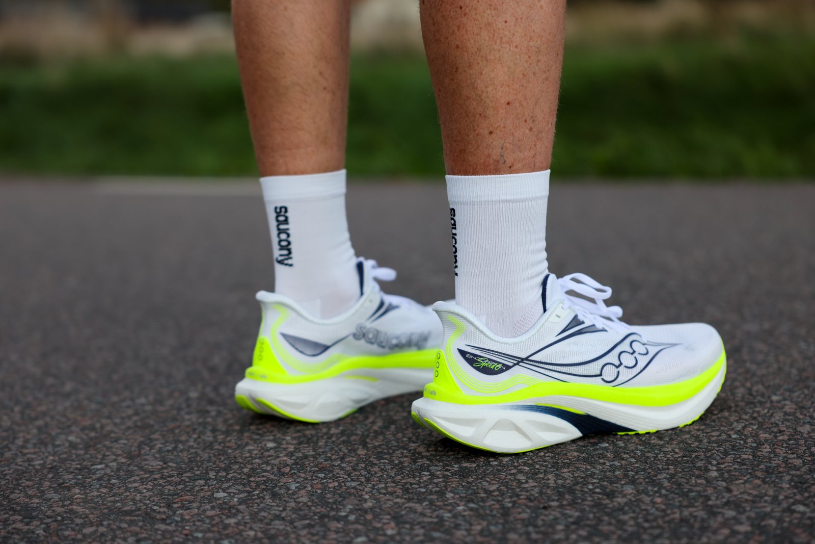 Saucony Endorphin Speed 6 i vitt och neongult på en löpares fötter